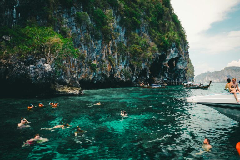 Swimmers enjoy the turquoise waters near limestone cliffs in Phuket, Thailand.